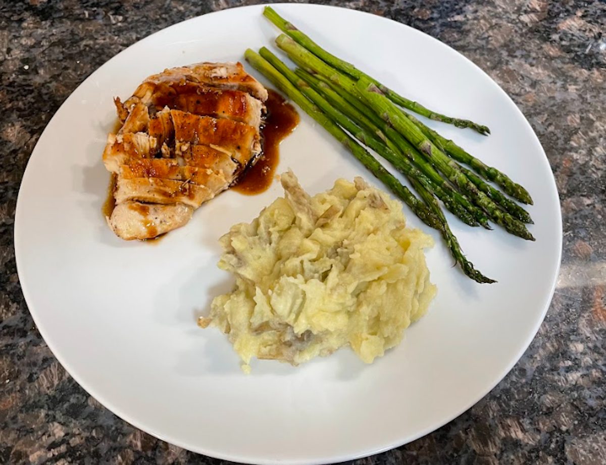 Cooked chicken and mashed potatoes with asparagus on a plate.
