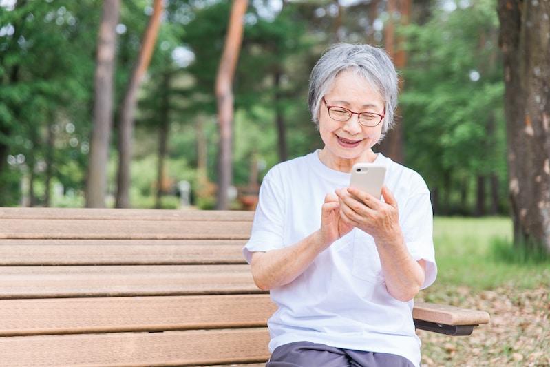 Woman using cell phone while sitting on park bench
