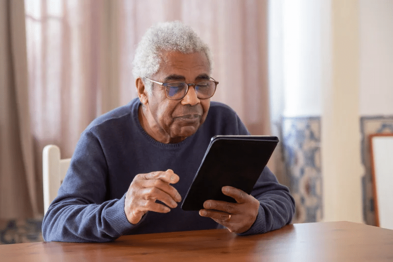 Older man in a blue sweater using a tablet to create his online will