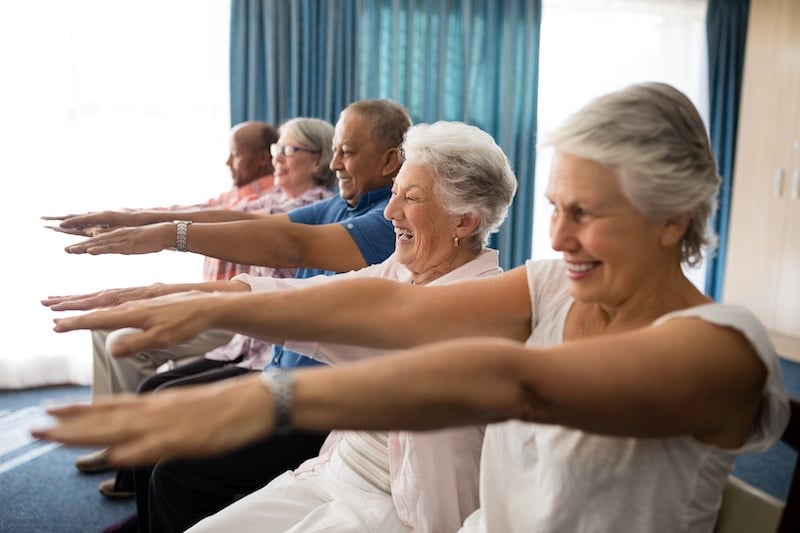 Older adults exercising while seated with hands outstretched