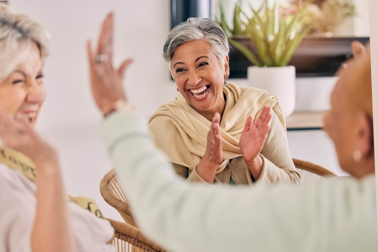 Elderly woman clapping and smiling with friends
