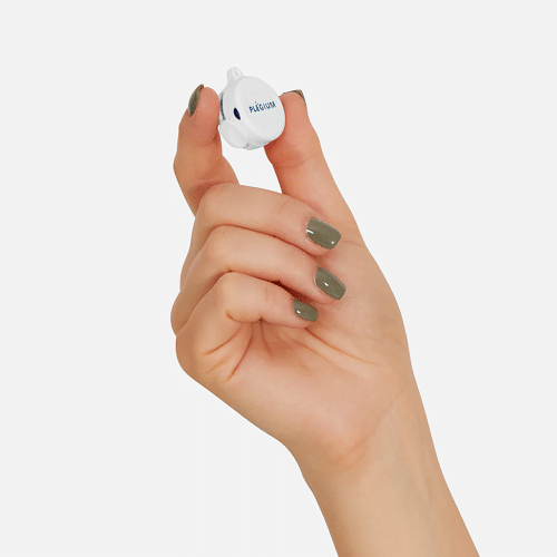 Close-up of a woman’s hand holding a Plegium Smart Emergency Button medical alert between thumb and forefinger