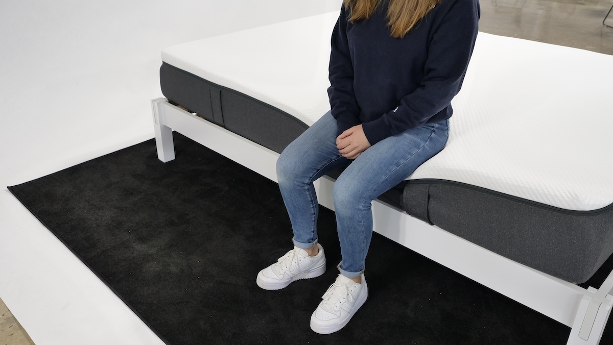 A person sitting on the Emma Original mattress edge. 
