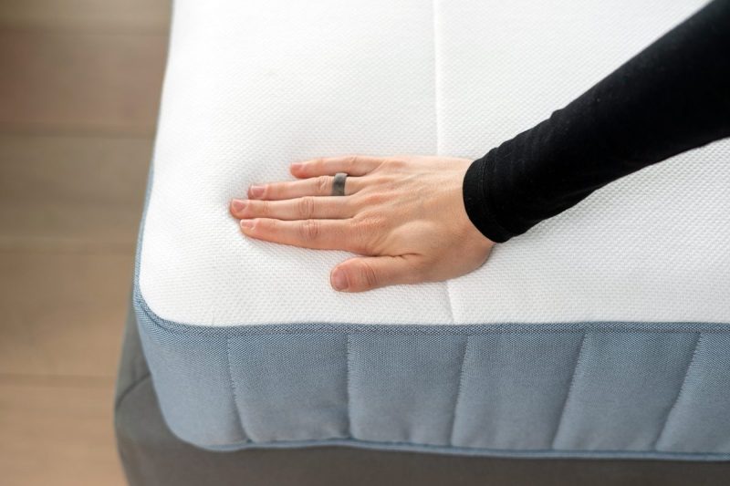 A person rubs their hand on a mattress top.