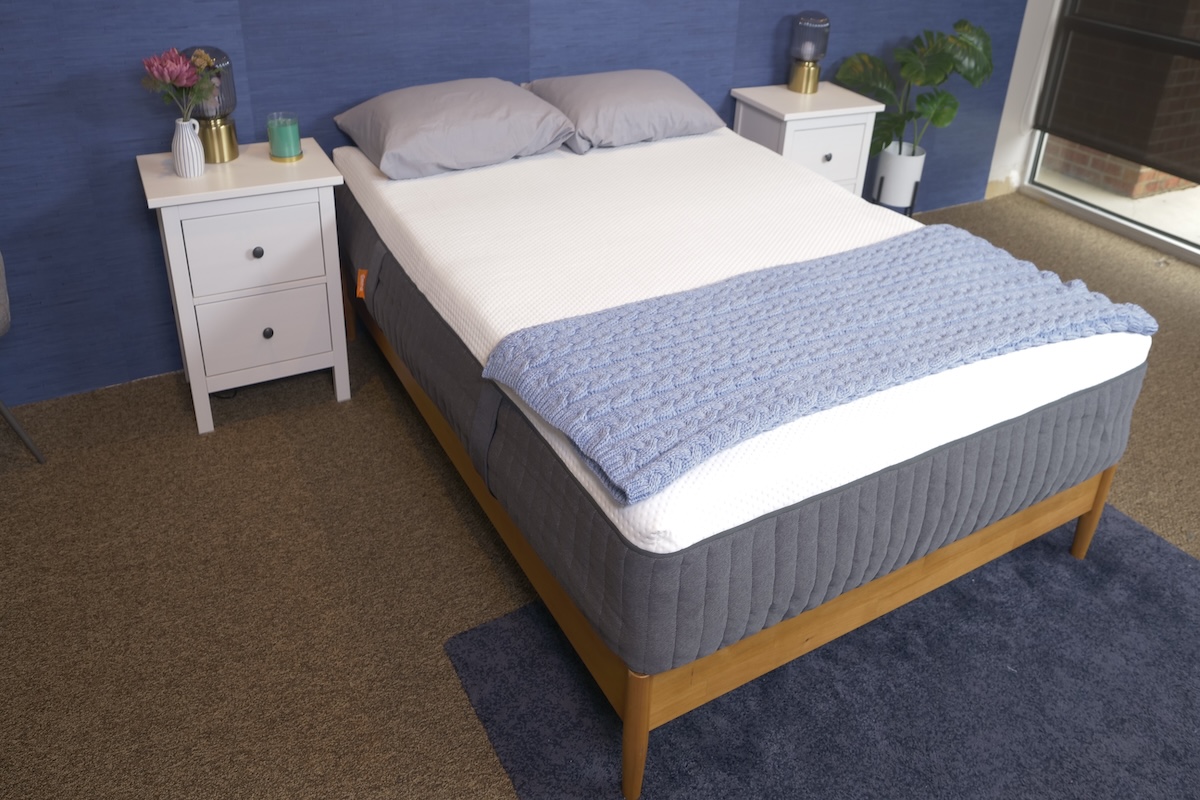  White and gray mattress in a bedroom with a blue blanket folded at the bottom