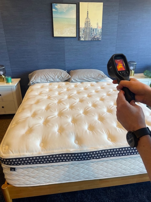 A tester using a temperature gun to measure the mattress’s temperature regulation.