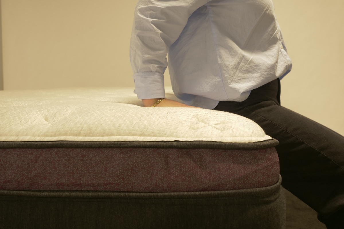 Tester sitting on the Helix Dusk Luxe mattress