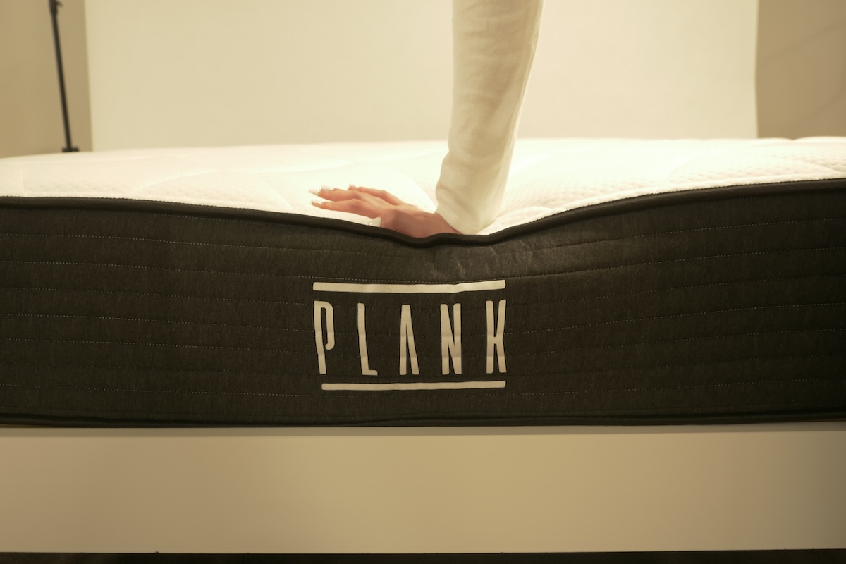  Tester pushing down on the surface of the Plank Firm mattress