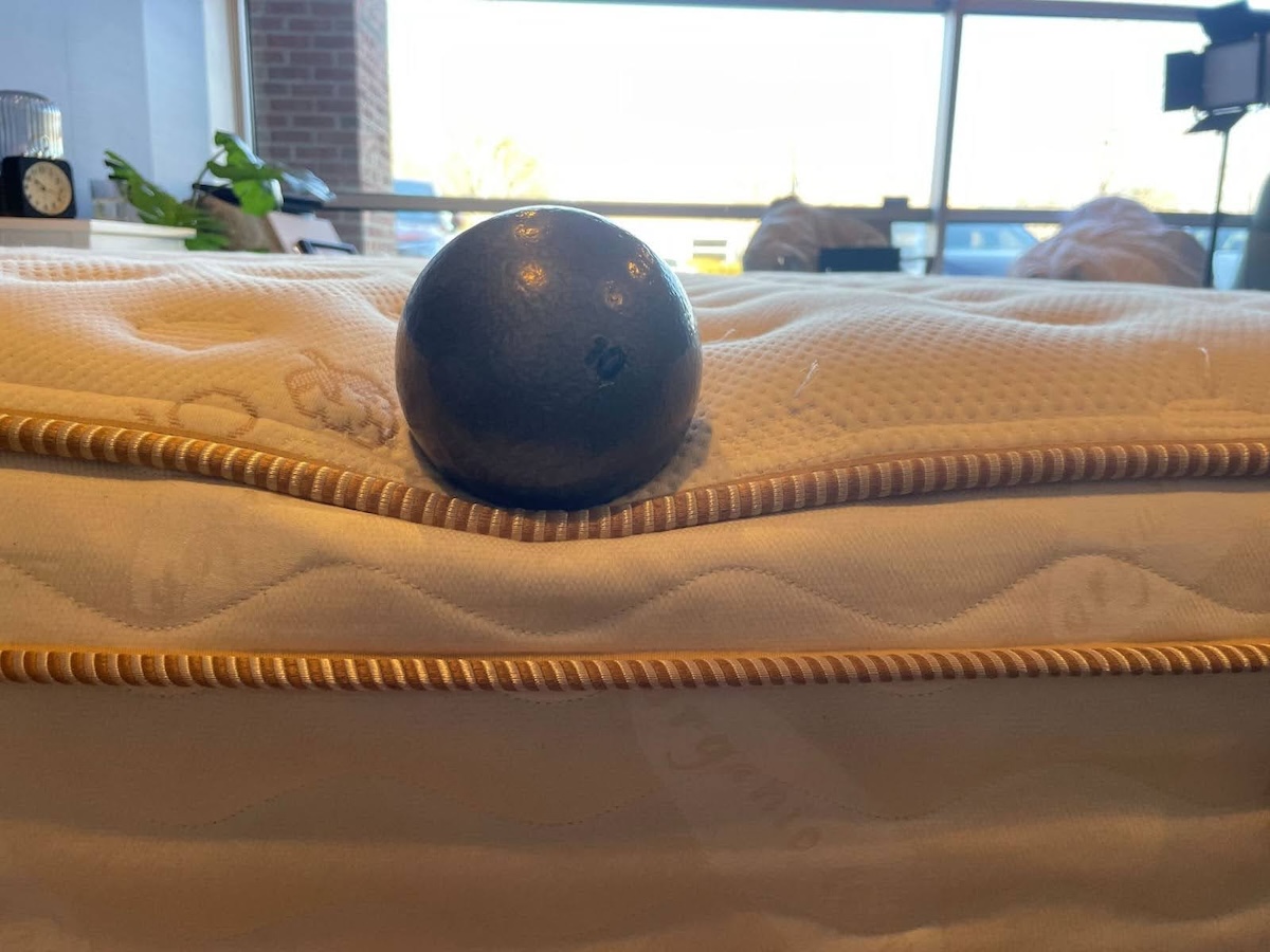 10-pound ball sits on the edge of the Saatva Classic without rolling off