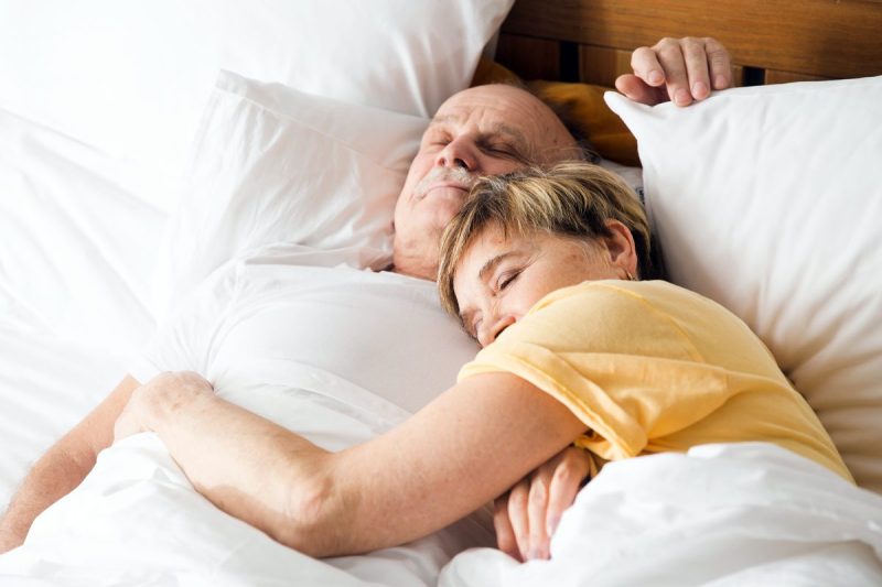 Man and woman sleeping close together in bed