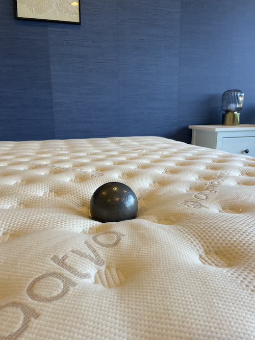 A Saatva Classic mattress with a weighted ball on top to test for mattress firmness.
