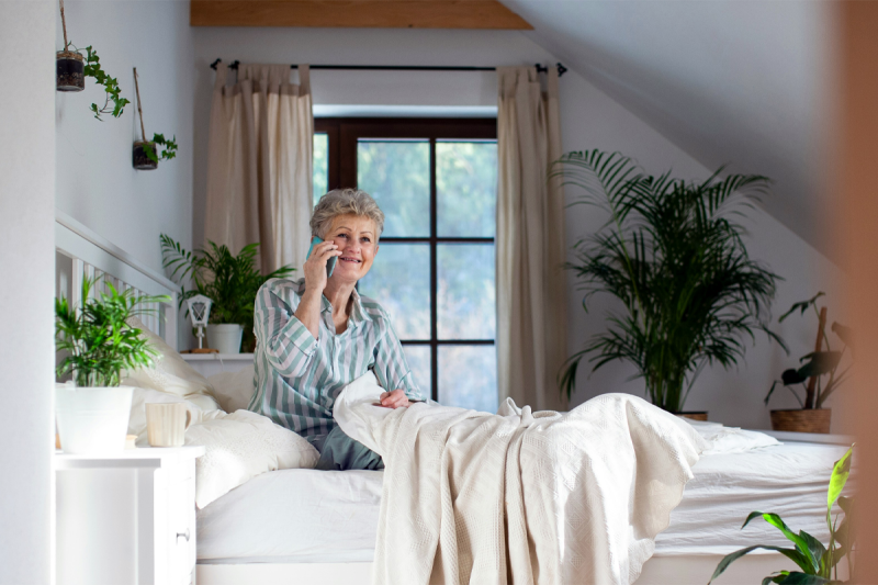 An older woman in a bed talking on a mobile phone
