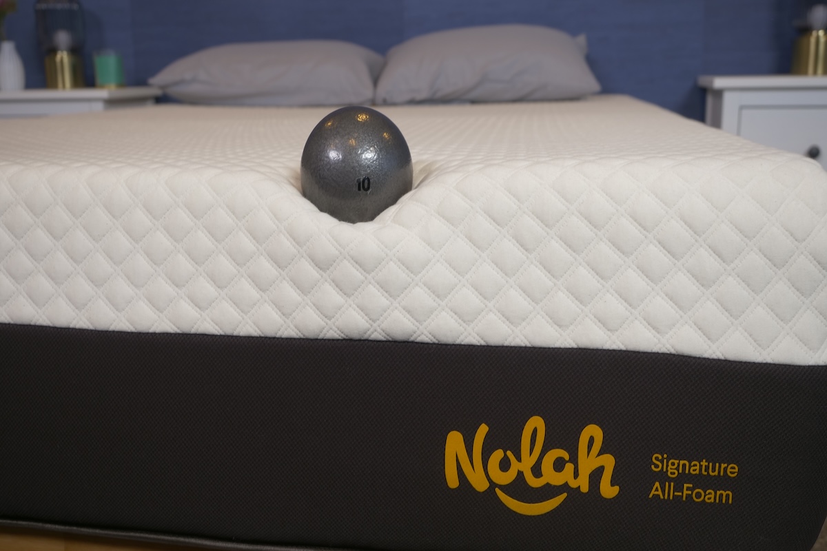A 10-pound ball rests on the edge of the Nolah Signature All-Foam mattress.