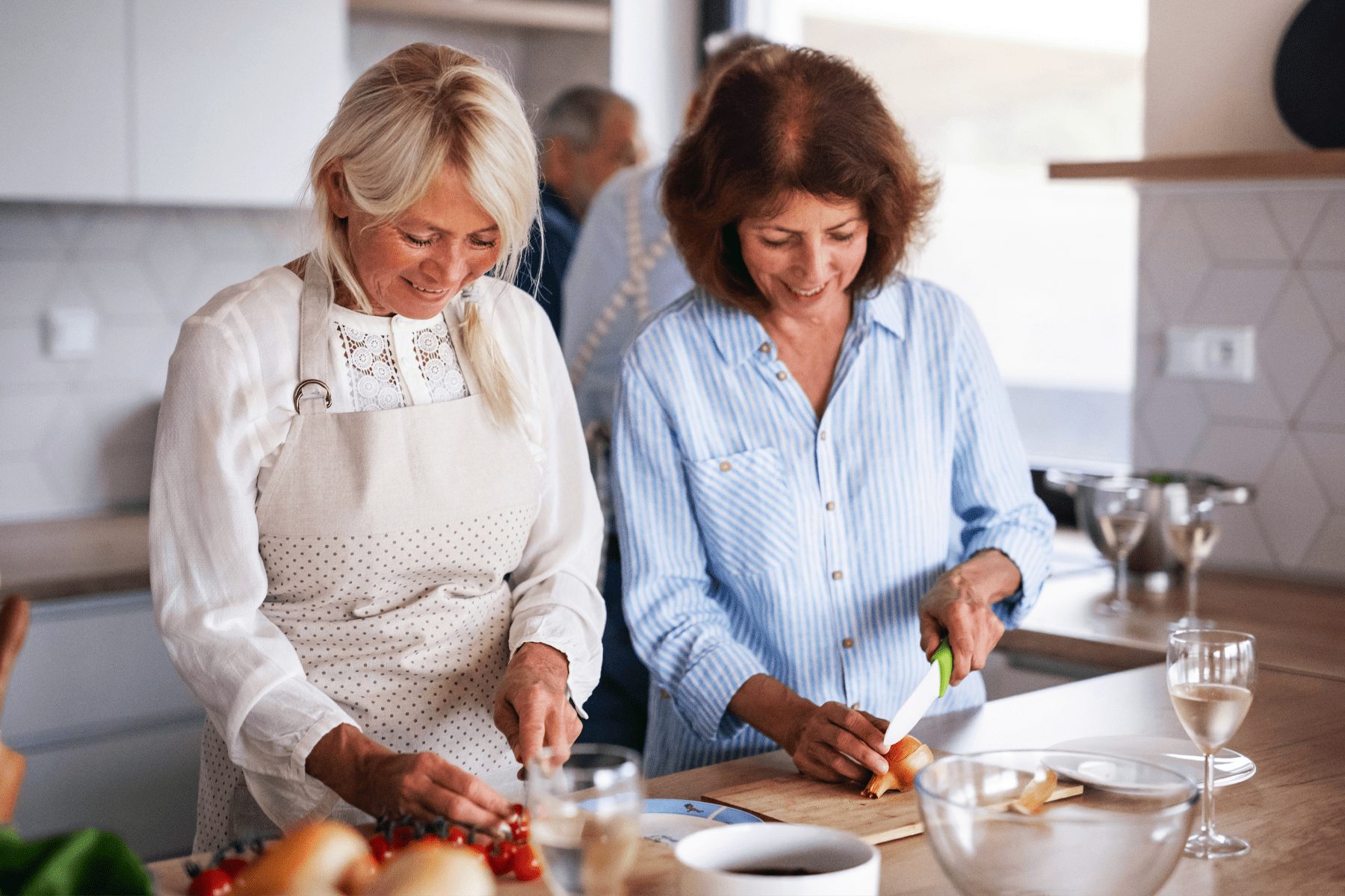 Two women smiling and chopping vegetables in a modern kitchen