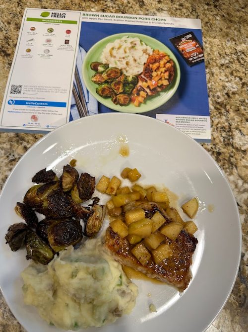 Brown sugar bourbon pork chops topped with apples and paired with mashed potatoes and roasted Brussels sprouts]