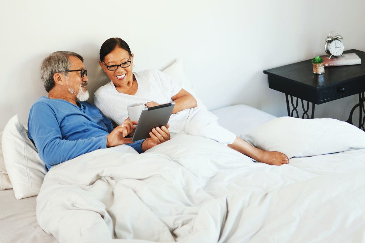 A couple looking at a touchscreen table in bed