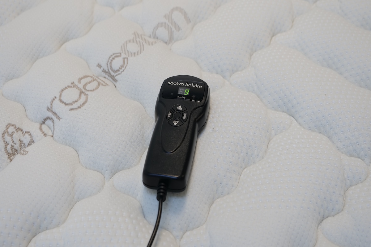  Black Saatva Solaire remote rests on the top of the bed with a white organic cotton cover.