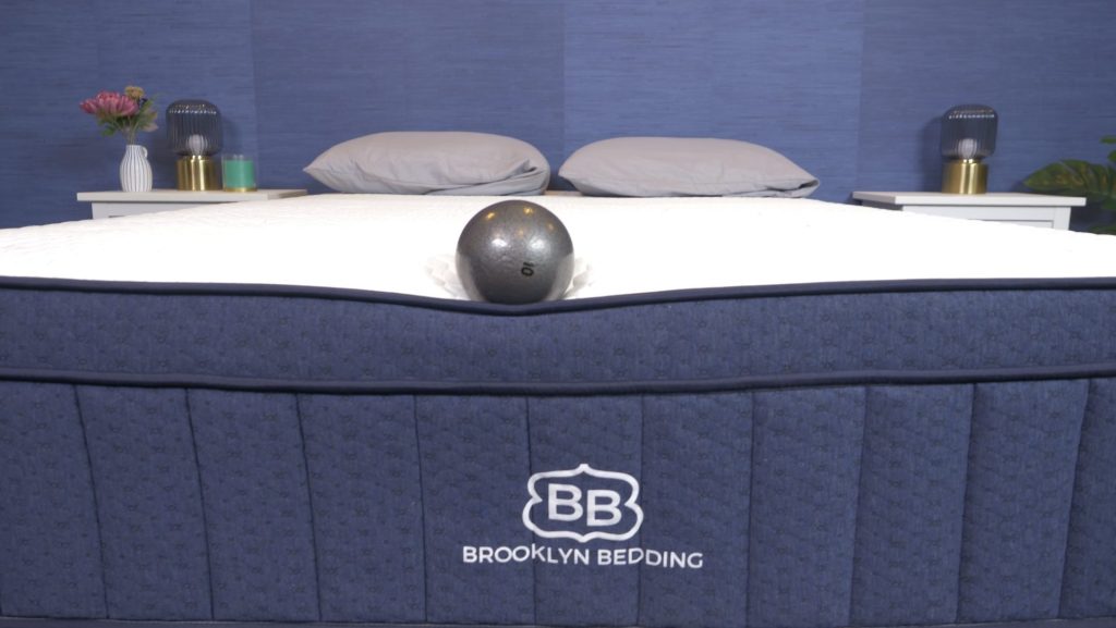 Our tester evaluating the edge support of the Brooklyn Bedding Aurora Luxe with a bowling ball.
