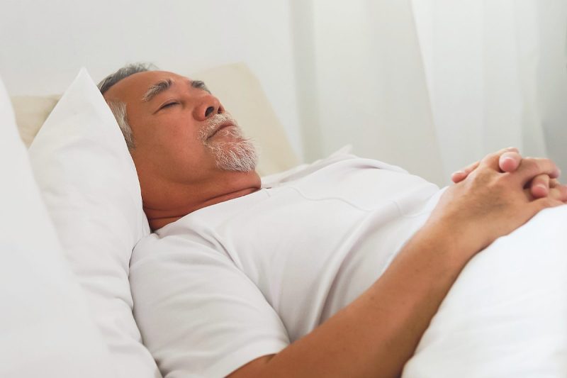 Man wearing white sleeps on his back