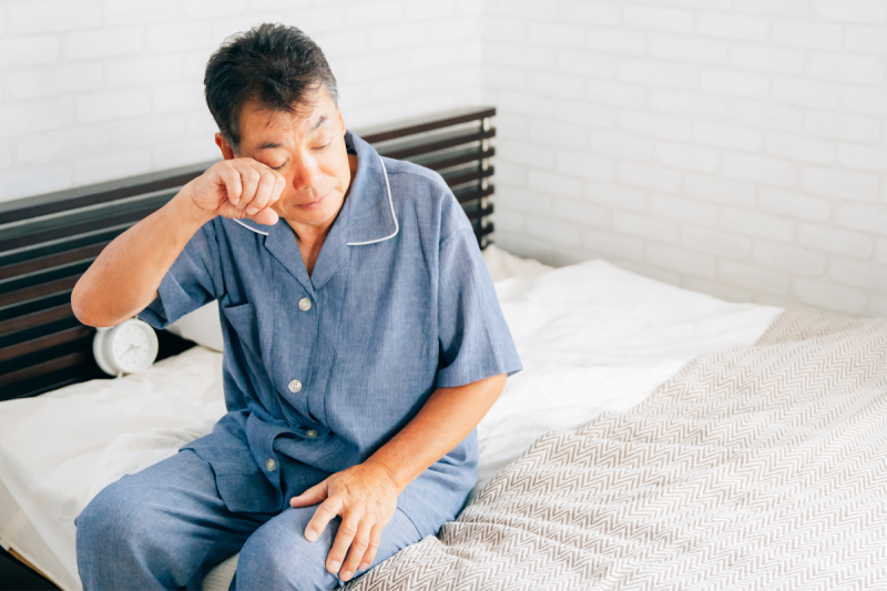 sleepy man sits up in bed