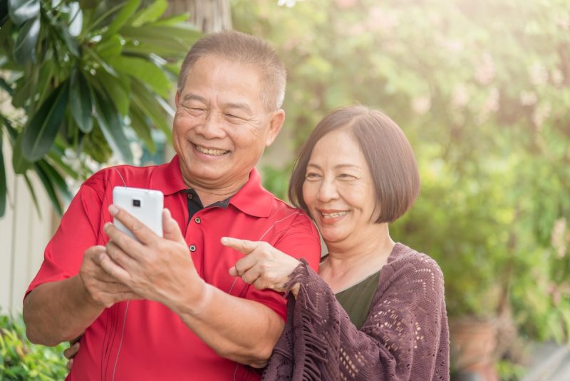 two people smile while looking at their cell phone