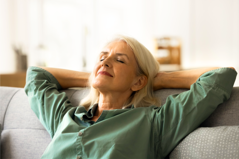 woman leans back with hands behind her head and eyes closed while smiling