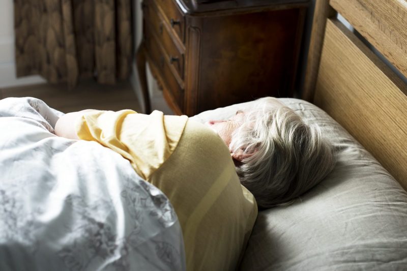 Woman sleeps in bed on her side