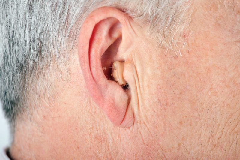 A hearing aid in an older man's right ear