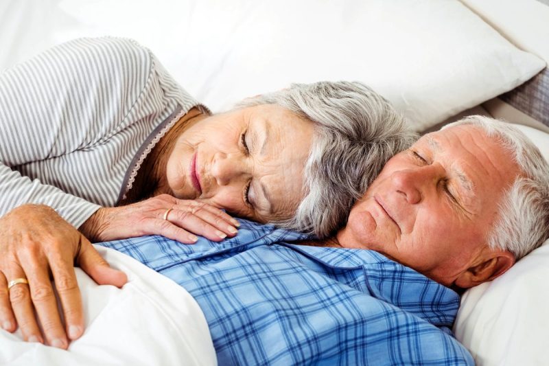 Man and woman snuggle and sleep in bed together