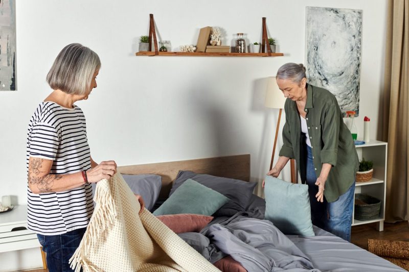 Two women make the bed together