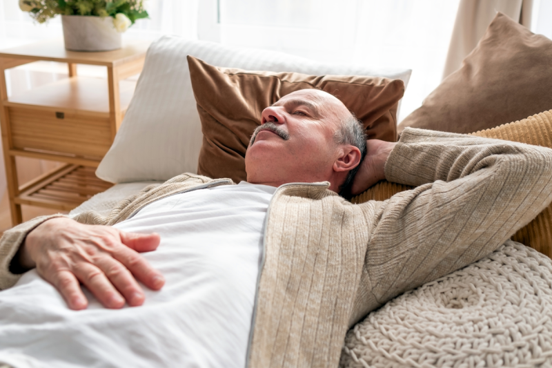 man naps on his back in his living room