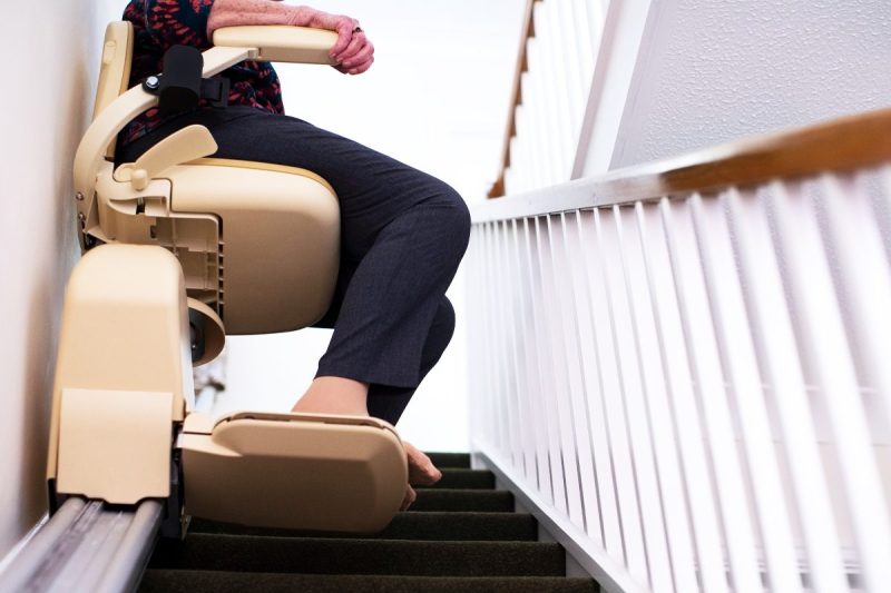 woman rides stair lift chair up the staircase