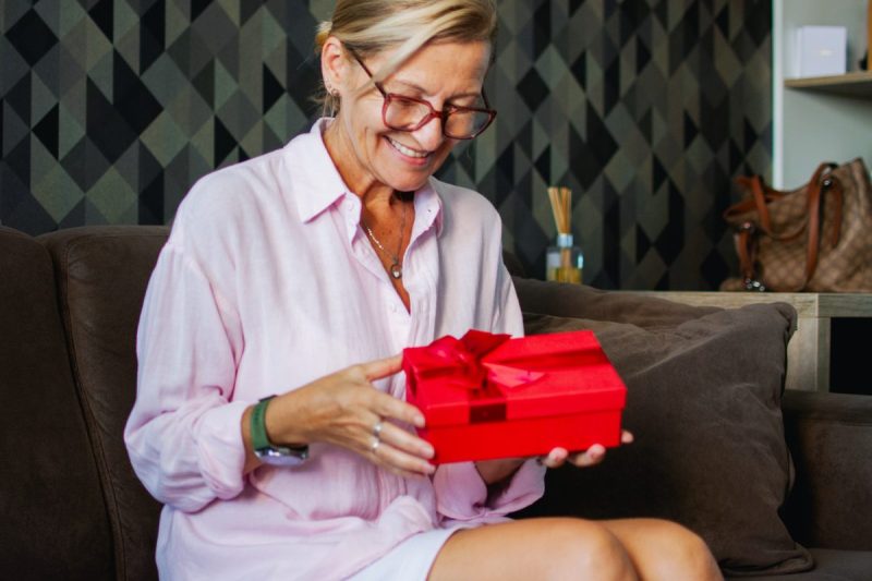 woman happily opens a red present