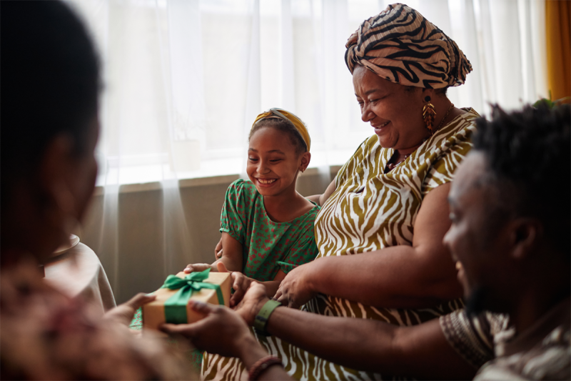 Woman happily opens gifts surrounded by her family