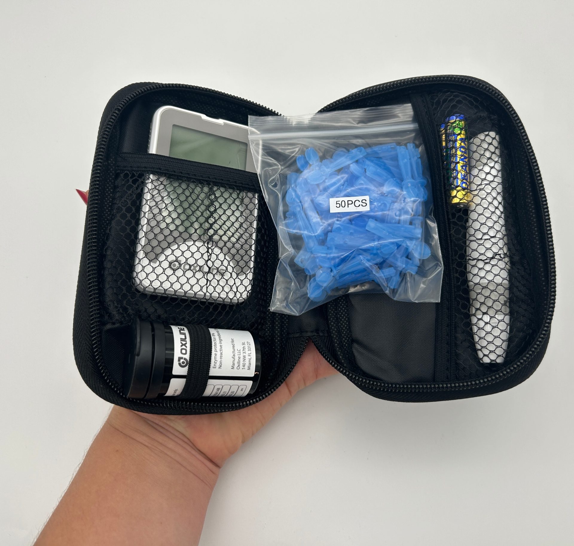 A person holding the open carrying case for the Oxiline Gluco X Pro glucose monitor and supplies