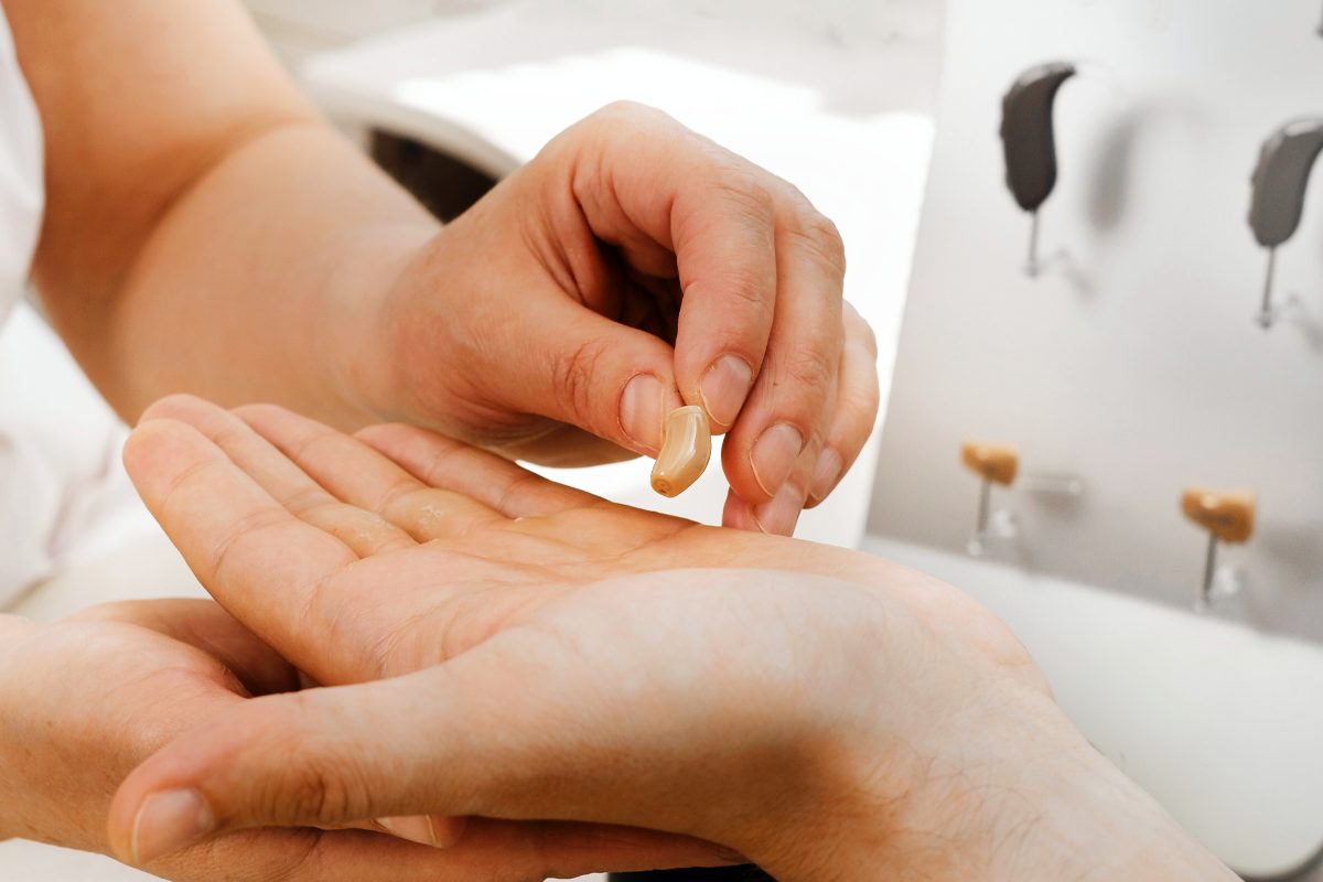 One person placing a hearing aid into the hand of another person